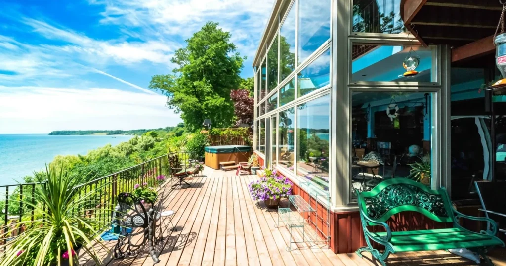 Waterfront deck beside a glass sunroom overlooking the shore