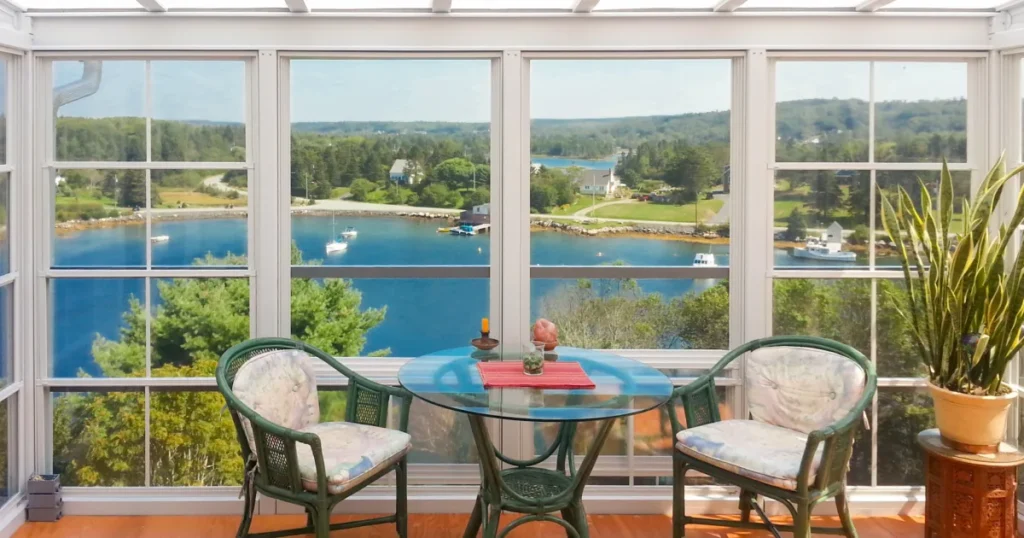 White-framed vinyl sunroom overlooking a quiet coastal inlet