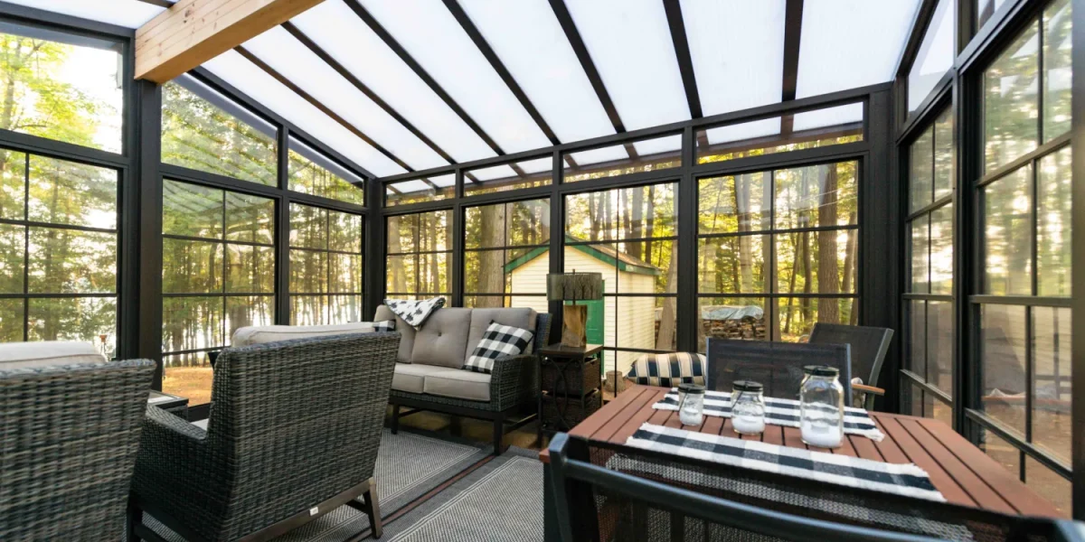 Black-framed vinyl sunroom with dining and lounge seating in warm evening light