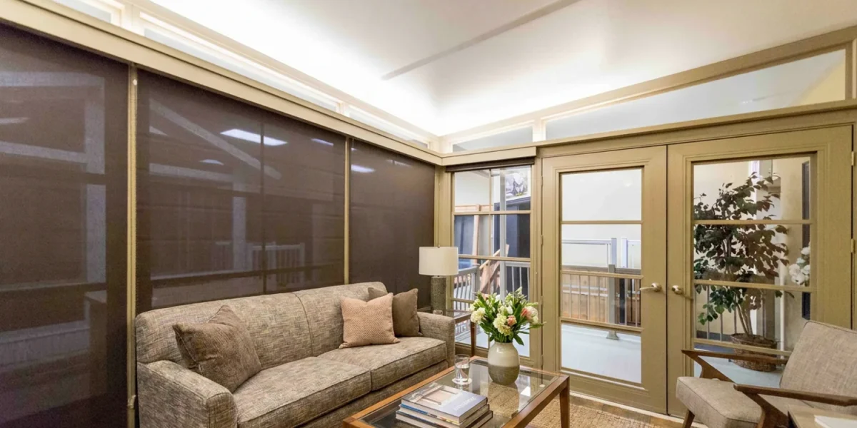 Dark solar shades lowered over sunroom windows to reduce afternoon heat